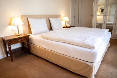 a bedroom with a large white bed with two lamps at Altstadthotel Messerschmitt in Bamberg