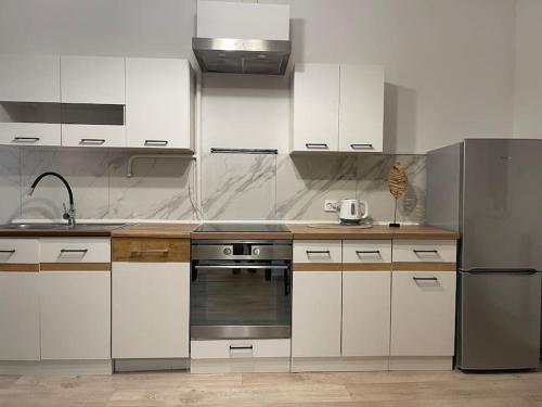 a kitchen with white cabinets and a stainless steel refrigerator at Dom w Nowym Sączu przy Miasteczku Galicyjskim in Nowy Sącz