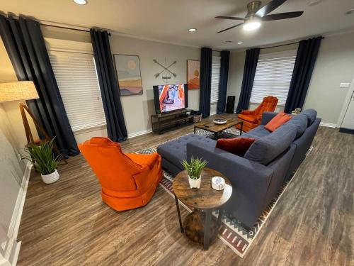 a living room with a blue couch and orange chairs at The Drover House by USAO in Chickasha, Fenced Yard, King Bed, Smart TV, High Speed WIFI & Covered Parking in Chickasha