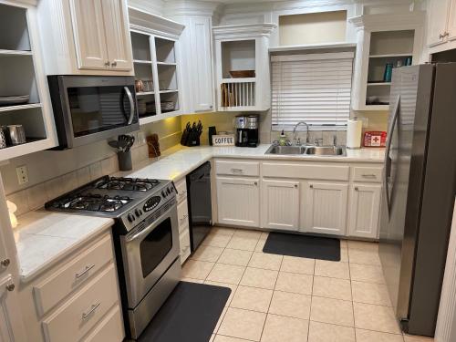 a kitchen with white cabinets and a stove top oven at The Drover House by USAO in Chickasha, Fenced Yard, King Bed, Smart TV, High Speed WIFI & Covered Parking in Chickasha