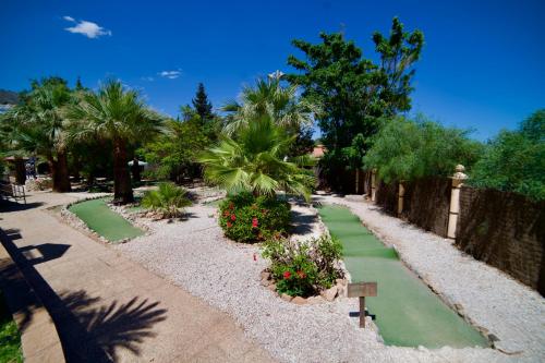 a garden with green paths and trees and palm trees at Holiday Premium Resort in Benalmádena