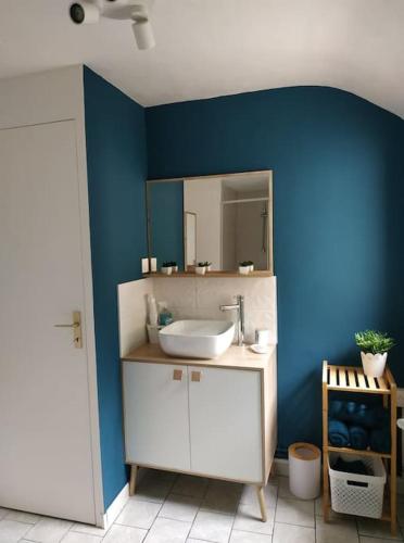 La salle de bains est pourvue d'un lavabo et d'un mur bleu. dans l'établissement la Lillebonnaise meublé au cœur de Lillebonne, à Lillebonne