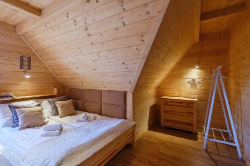 a bed in a wooden room with a ladder at Michałowy Sen Domki Zakopane in Zakopane