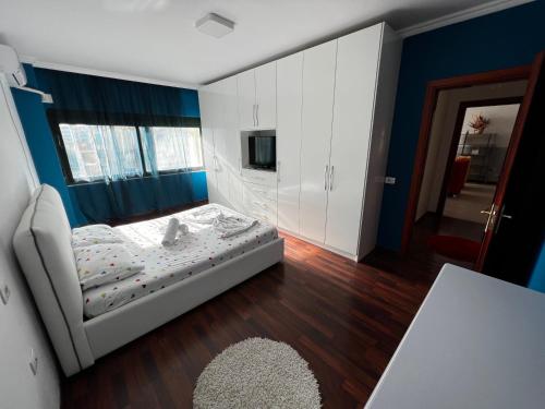 a bedroom with a white bed and a blue wall at SunShine APARTMENT in Tirana