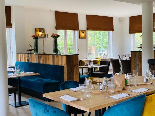 OostrozebekeにあるHotel Swaenenburgの木製テーブルと青い椅子が備わるレストラン