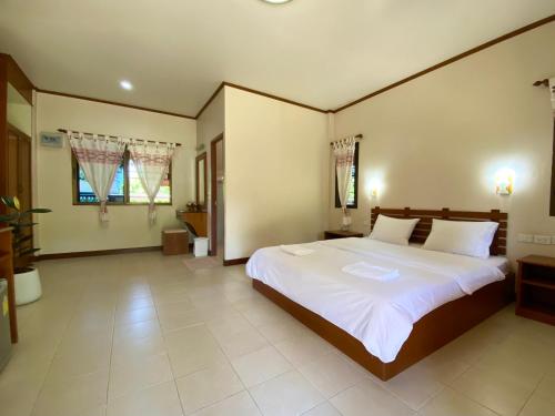 a bedroom with a large bed with white sheets at Mom and Me Resort & Farm in Doi Saket