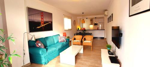 Una sala de estar con un sofá azul y una cocina. en Maravilloso apartamento, en Nerja