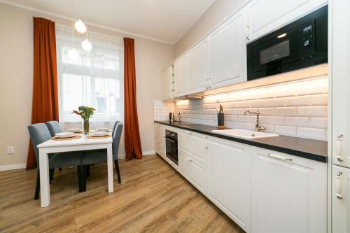 eine Küche mit weißen Schränken, einem Tisch und einem Waschbecken in der Unterkunft New apartment 1 - self check in, free parking in Bratislava