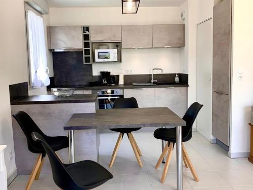 une cuisine avec une table en bois et des chaises noires dans l'établissement Appartement 3 étoiles, calme et confort à deux pas de la plage et du port de Mèze - FR-1-604-27, à Mèze