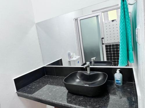 baño con lavabo negro y espejo en Sunshine Residence, en Poste Lafayette