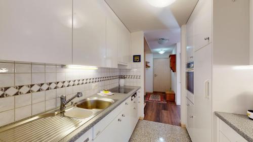 a white kitchen with a sink and a counter at Truoch in Samedan