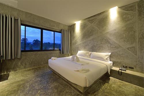 Un dormitorio con una gran cama blanca y una ventana en The Oasis Resort, en Krabi