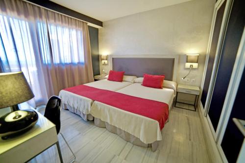a hotel room with a large bed with red pillows at Casamaïa Apartments in Benalmádena