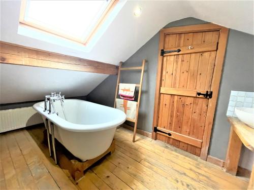 a bathroom with a large bath tub and a skylight at Inglefall & Jasmine Cottages in Ingleton 