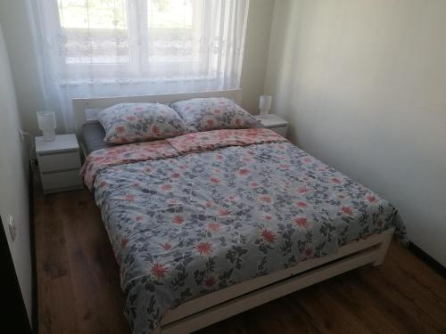 een slaapkamer met een bed met een bloemdekbed en een raam bij mieszkanko w centrum Iławy in Iława