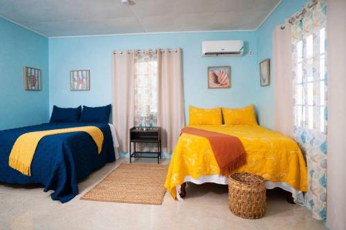 two beds in a room with blue walls at Treasured Gem Hideaway in Treasure Beach