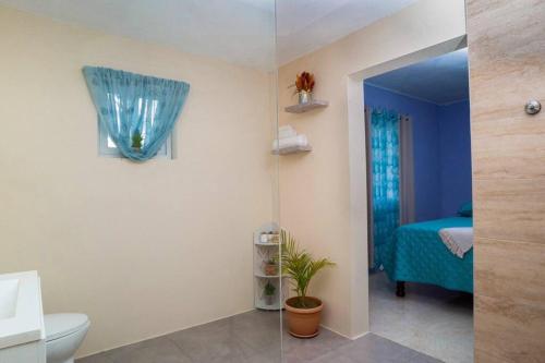a bathroom with a toilet and a room with a bed at Treasured Gem Hideaway in Treasure Beach