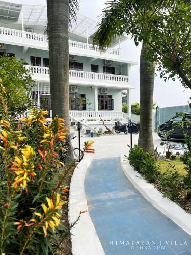 una pasarela frente a un edificio con palmeras en Himalayan Villa, en Dehradun