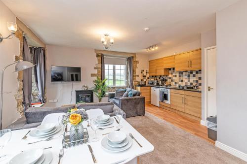 a living room with a table and a kitchen at Bridge End Mill by Guestz in Settle