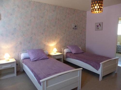 - 2 lits dans une chambre avec des draps et des lampes violets dans l'établissement Maison cosy à Moulins : proche centre, cour fleurie, vélos, WiFi et draps fournis - FR-1-489-162, à Moulins