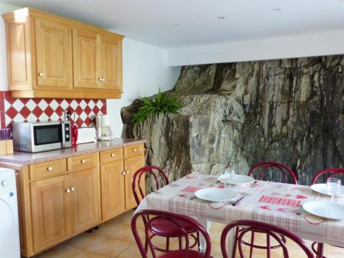 Il comprend une cuisine équipée d'une table avec des chaises rouges et d'un four micro-ondes. dans l'établissement Ancien moulin rénové, idéal pour familles : nature, jeux, pêche, proche de Vichy, tout confort inclus - FR-1-489-212, à Ferrières-sur-Sichon