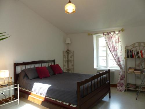 Un dormitorio con una cama con almohadas rojas y una ventana en Gîte Ferrières-sur-Sichon, 4 pièces, 6 personnes - FR-1-489-191, en Ferrières-sur-Sichon