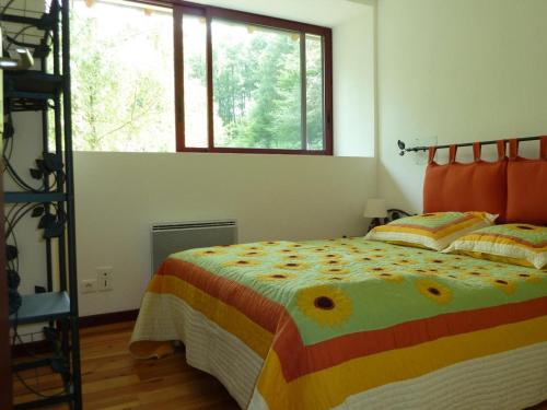 une chambre avec un lit avec une couette colorée et une fenêtre dans l'établissement Ancien moulin rénové, idéal pour familles : nature, jeux, pêche, proche de Vichy, tout confort inclus - FR-1-489-212, à Ferrières-sur-Sichon