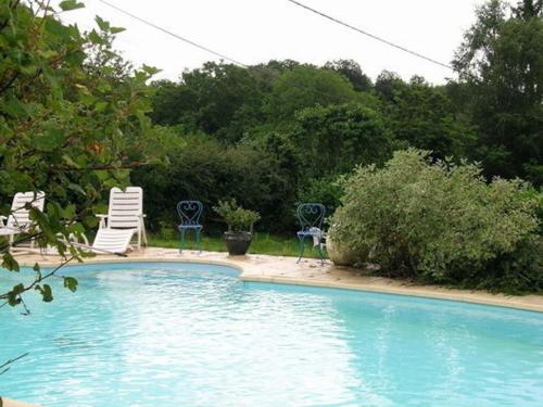 a swimming pool with two lawn chairs and two chairs at Chalet familial 5 pers. au vert avec terrasse en Auvergne - FR-1-489-323 in Échassières
