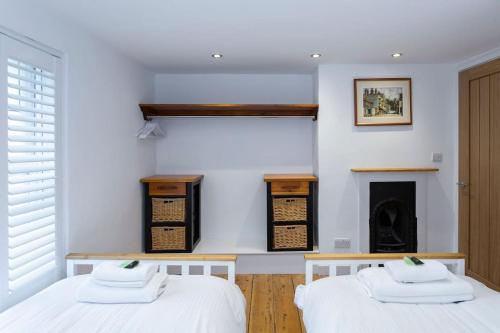 two beds in a room with a fireplace at Pickwick's Place By The Sea Broadstairs in Broadstairs