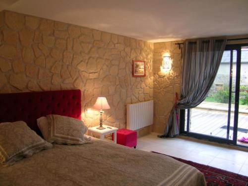 a bedroom with a bed with a stone wall at Grande maison calme avec piscine chauffée en Auvergne - FR-1-489-346 in Saint-Hilaire