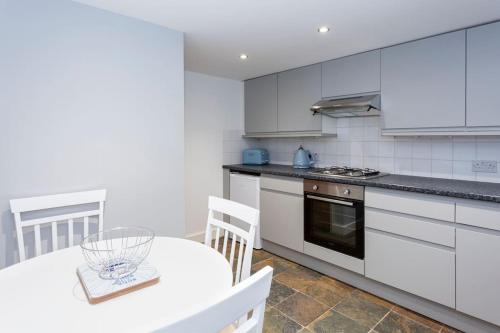 a kitchen with white cabinets and a table with a bowl on it at Pickwick's Place By The Sea Broadstairs in Broadstairs