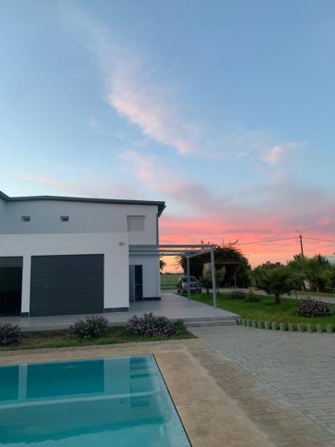 a house with a swimming pool in front of a sunset at Magnifique villa avec piscine in Kenitra