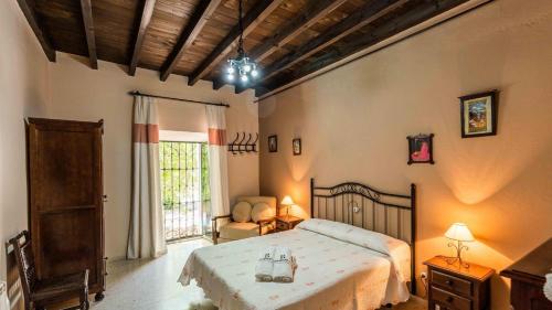 een slaapkamer met een bed, een stoel en een raam bij Cortijo Coracho Osuna by Ruralidays in Saucejo