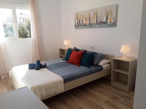1 dormitorio con 1 cama con almohadas azules y rojas en Beach and Pools La Cala Mijas & Fuengirola by H&H, en Fuengirola