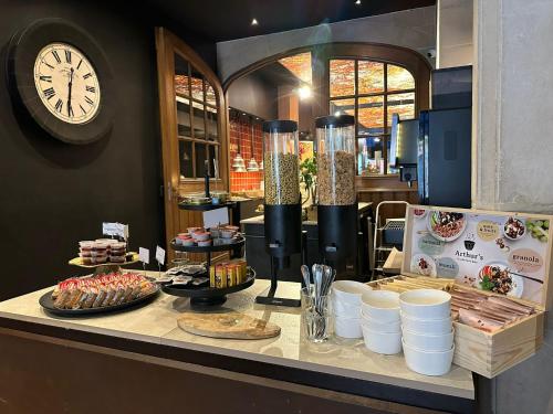 a counter with food and a clock on the wall at Hotel Cortina in Wevelgem