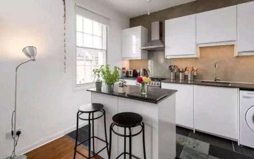 a kitchen with white cabinets and two bar stools at University and Central Edinburgh in Edinburgh