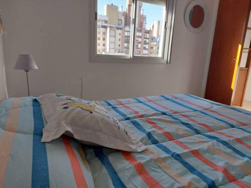 1 cama con un edredón colorido en un dormitorio con ventana en Departamento nuevo en Cordoba en Córdoba