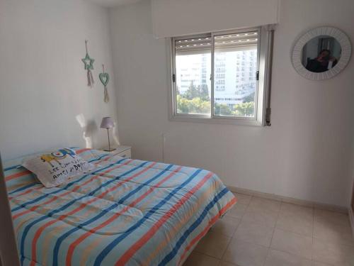 1 dormitorio con cama, ventana y espejo en Departamento nuevo en Cordoba en Córdoba