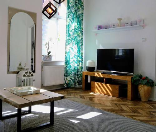 a living room with a flat screen tv and a table at Apartament Mickiewicz - Center in Słupsk