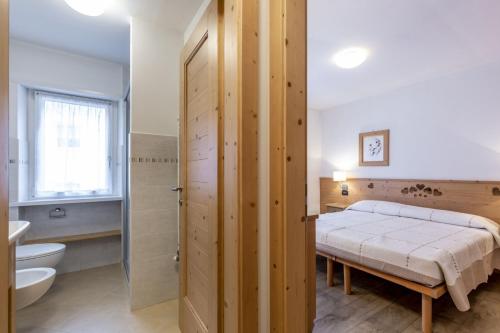 una camera con letto, servizi igienici e lavandino di Stella Alpina a Campitello di Fassa