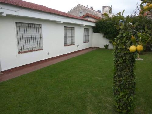 un patio trasero con césped verde y una casa blanca en Chalet MIRAMAR Zona II para 6 Pax en Miramar