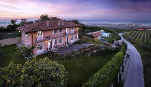 a large pink house on a hill with a road at Villa Bricco dei Cogni in La Morra