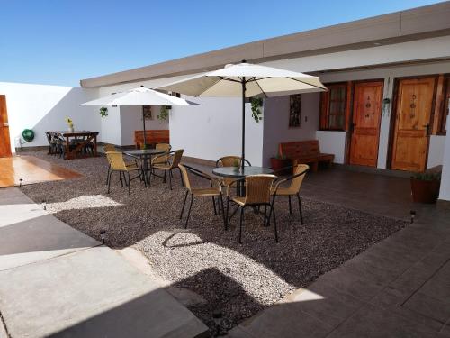 un patio con mesas, sillas y sombrillas en Hostal Belen, en San Pedro de Atacama