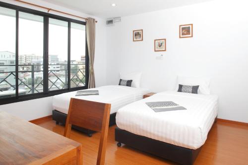 two beds in a room with a large window at Double DD House at MRT Sutthisarn in Bangkok
