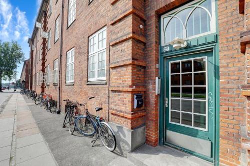 コペンハーゲンにあるCosy room in residential part of Copenhagen, with free street parking and shared bathroomの煉瓦造りの建物の脇に停められた自転車の一団