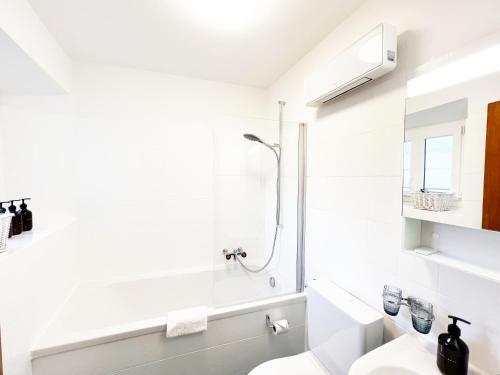 La salle de bains blanche est pourvue d'une douche et de toilettes. dans l'établissement Boho Lake House - Private Beach 600m from the property - Free Parking - Home Cinema Room, à Vira