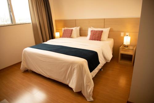 1 dormitorio con 1 cama grande con sábanas y almohadas blancas en Hotel Franco en Dionísio Cerqueira
