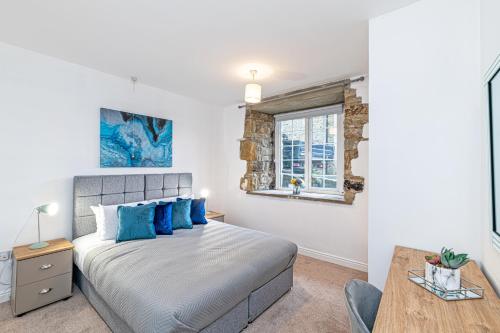 a bedroom with a bed with blue pillows and a table at Bridge End Mill Apartments In Settle in Settle