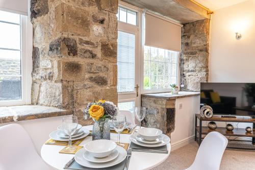 a dining room with a table and chairs and a stone wall at Bridge End Mill by Guestz in Settle