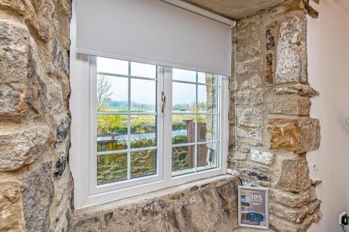 a window in a room with a stone wall at Bridge End Mill by Guestz in Settle